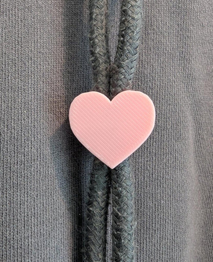 Pink heart-shaped zipper pull on a gray background