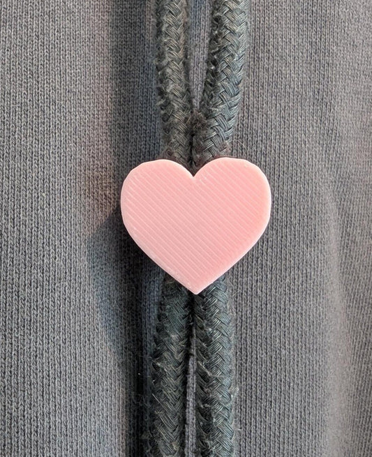 Pink heart-shaped zipper pull on a gray background