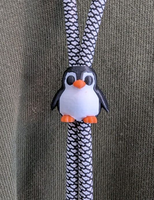 Penguin-shaped shoelace holder on a textured surface