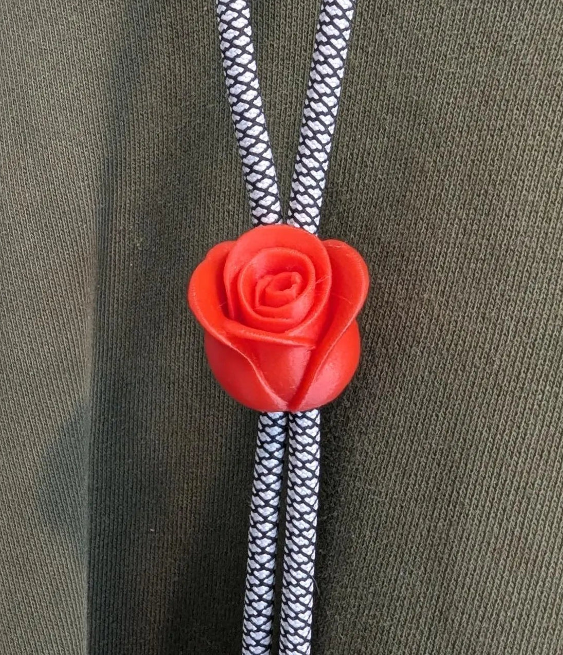 Red rose-shaped bolo tie on a green hoodie